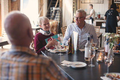 Senior friends talking while having lunch at table in restaurant