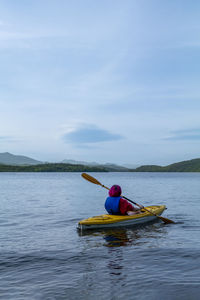 Man kayaking in sea against sky