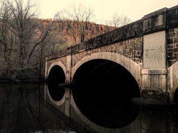 Arch bridge over river against sky