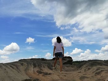 Rear view of woman on rock against sky