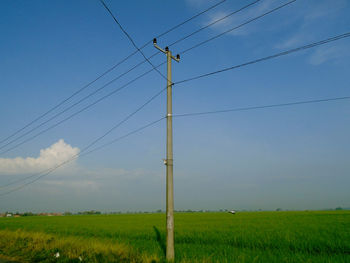 Low angle view of electricity pylon on field against sky