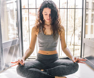 Young girl doing yoga at the window