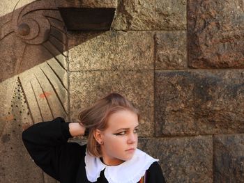 Portrait of young woman standing against wall