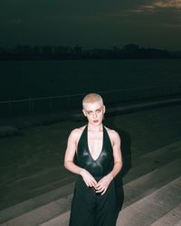 Portrait of young woman standing against sea