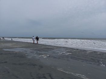 People walking on beach against sky