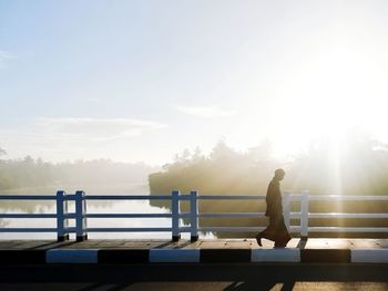 Man walking on the bridge against rising sky