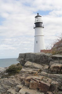 Lighthouse by sea against sky