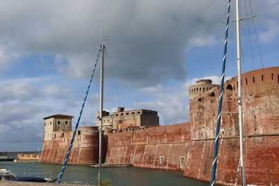 View of old building by sea against sky. old medici port in livorno, tuscany.