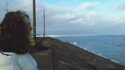 Rear view of woman on beach against sky