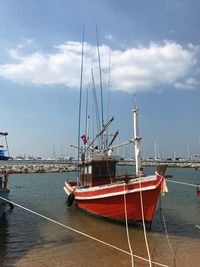 Sailboats moored on harbor against sky