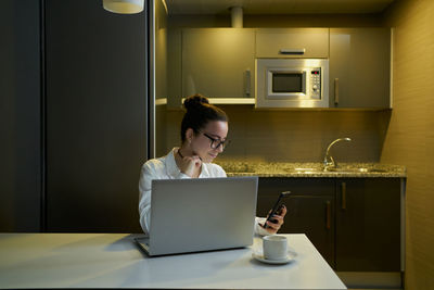 Young woman working with laptop in evening