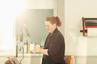 Side view of female mechanic washing hands in auto repair shop