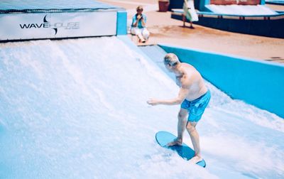 Full length of shirtless man jumping in swimming pool