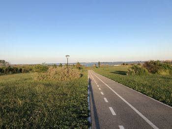 Road amidst field against clear sky