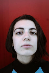 Close-up portrait of young woman against red background