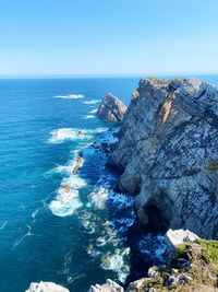 Rock formations in sea against clear blue sky