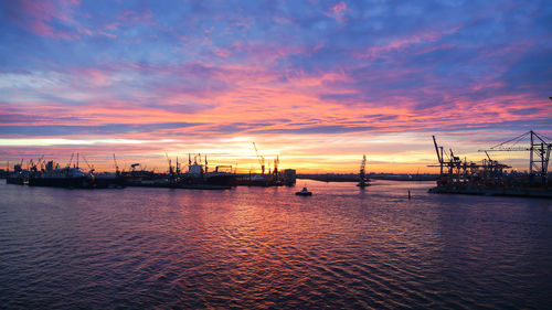 Boats moored at harbor against sky during sunset