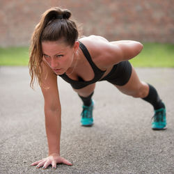 Mid adult woman doing push-ups on road