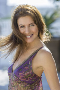 Portrait of smiling mid adult woman with brown hair standing outdoors