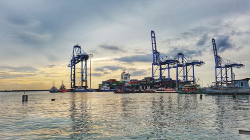 Cranes at commercial dock against sky