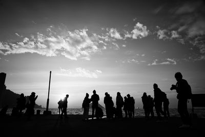 Silhouette people standing against sky during sunset