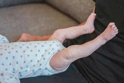 Midsection of father with baby feet at home
