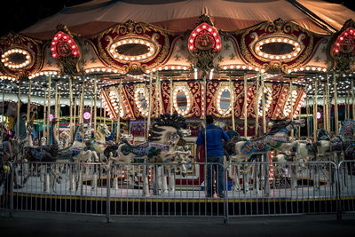 Illuminated carousel in amusement park at night