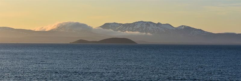 Scenic view of sea and mountains against sky during sunset