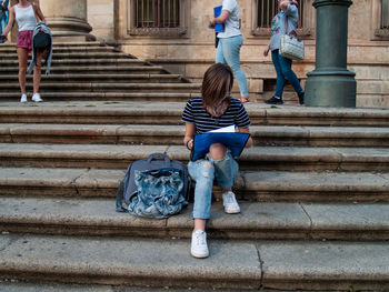 Teenage girl looking at file while sitting on staircase