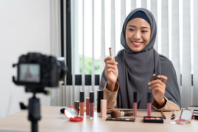 Woman in hijab showing makeup tutorials in front of camera