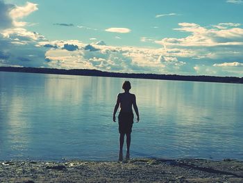 Full length of man standing in lake against sky during sunset