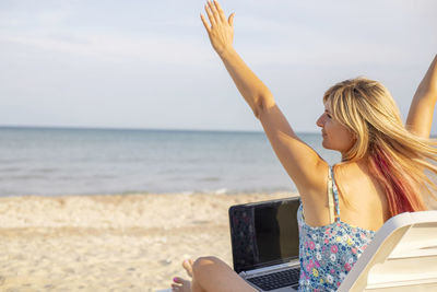 Young woman using laptop at beach