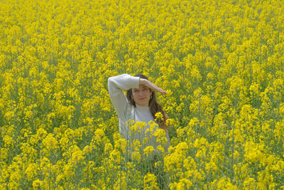 Close-up of yellow flowering plants on field and a girl in the middle