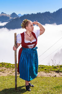 Young woman standing on field against mountains