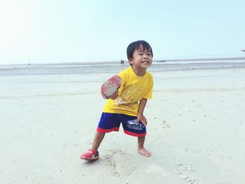 Full length of boy playing at beach against sky