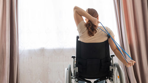 Rear view of woman sitting on wheelchair
