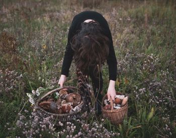 Woman bending with mushrooms in baskets on grassy field