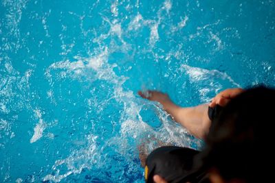 Low section of woman splashing water in swimming pool