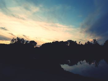 Silhouette trees by lake against sky during sunset