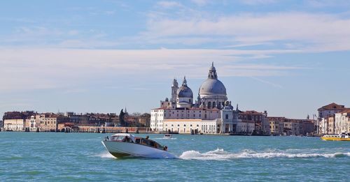 Motorboat in sea with santa maria della salute against sky