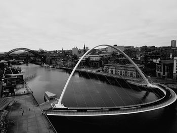 Modern bridge over river in city against sky