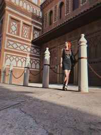 Full length of woman standing against building