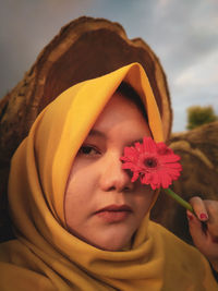 Close-up portrait of cute girl holding red flower