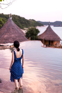 Rear view of woman standing in water against sky