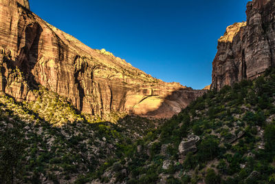 Low angle view of rocky mountain against blue sky