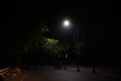 Empty road along trees at night