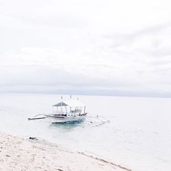 Boats in sea against cloudy sky