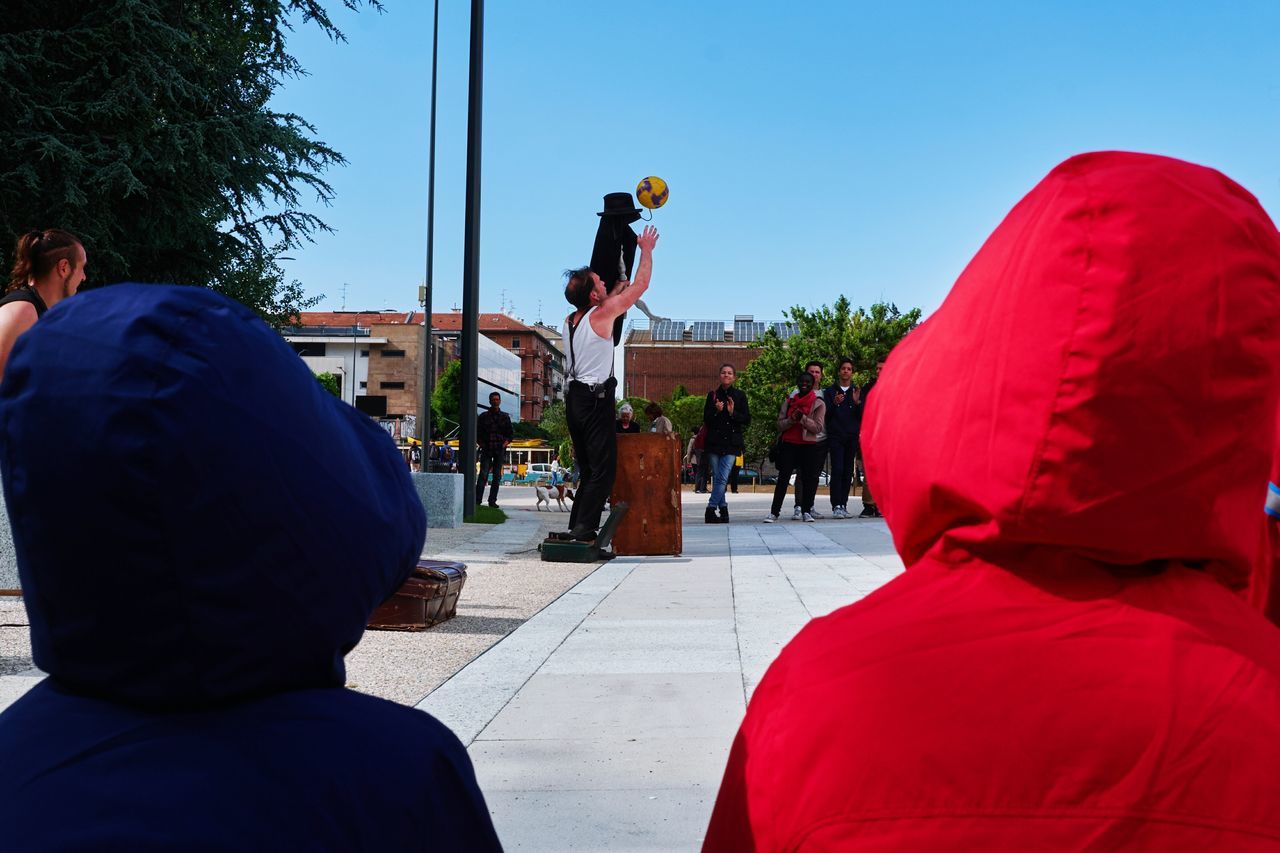 REAR VIEW OF BOY WITH ARMS RAISED AGAINST CLEAR SKY