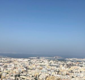 High angle view of townscape by sea against clear sky