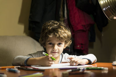 Portrait of boy sitting on table at home